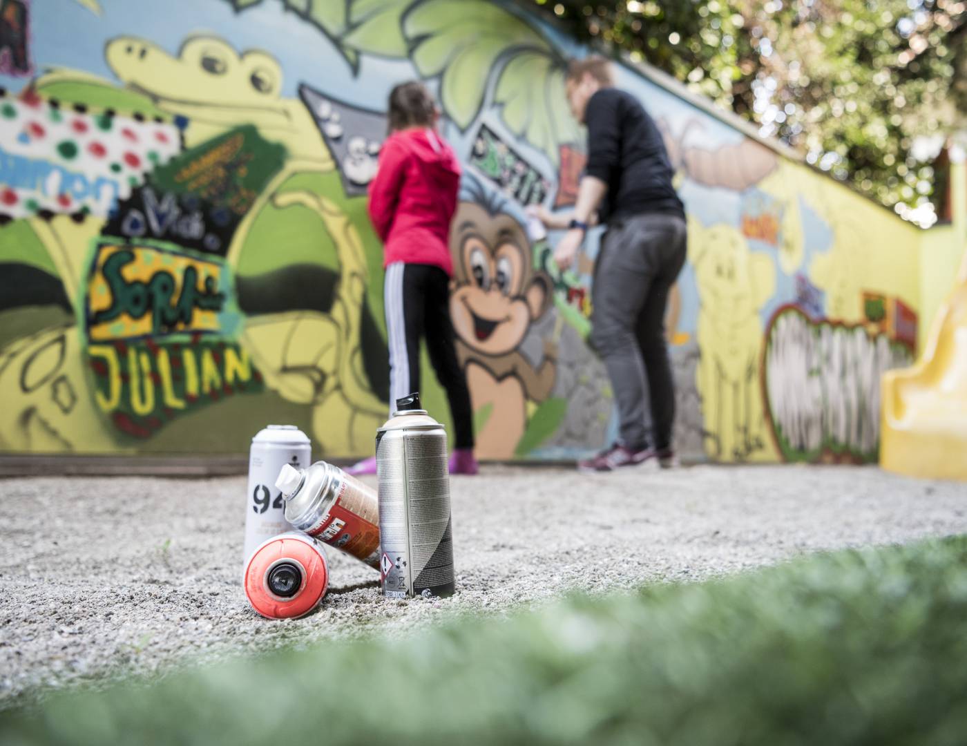 Kids entertainer and girl spray painting the wall of the kids club in a children’s hotel in South Tyrol