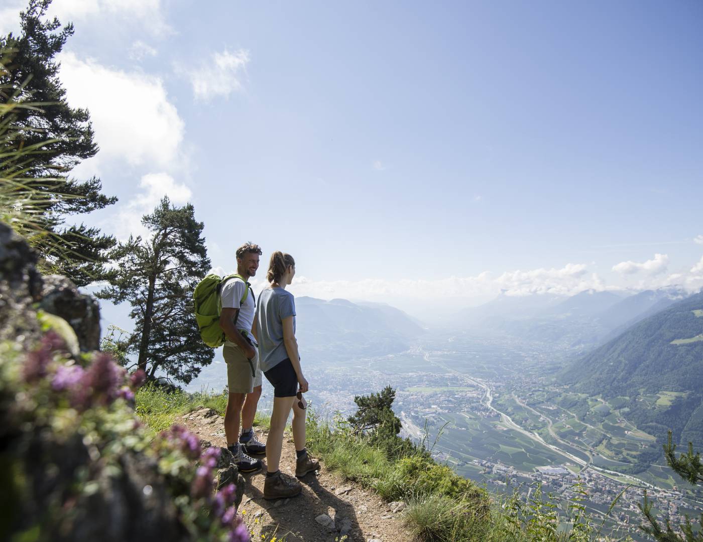 Pärchen wandert auf einem Höhenweg mit Panoramablick auf Meran