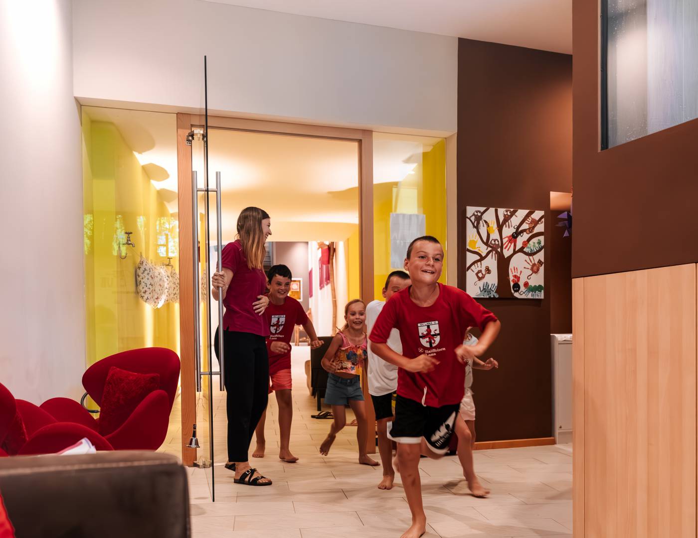 Jungs stürmen lachend in den Kidsclub des Kinderhotels und freuen sich aufs Spielen