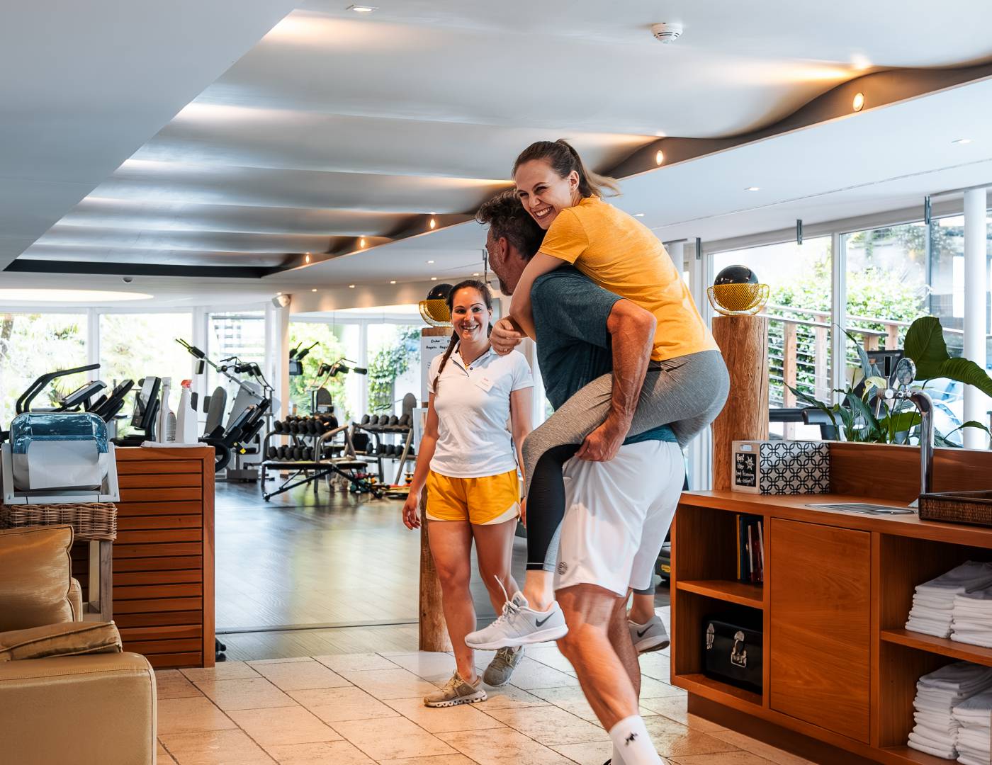 Lachendes Pärchen auf dem Weg in den modernen Fitnessraum des Wellnesshotels in Dorf Tirol, Südtirol