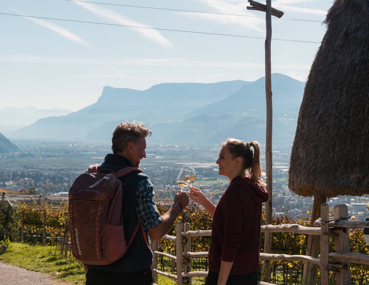 Pärchen stößt mit zwei Weingläsern über Meran an