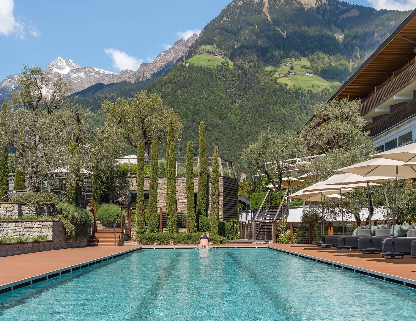 Schwimmer springt dynamisch in das 25-Meter-Sportbecken des Hotel Erika in Dorf Tirol