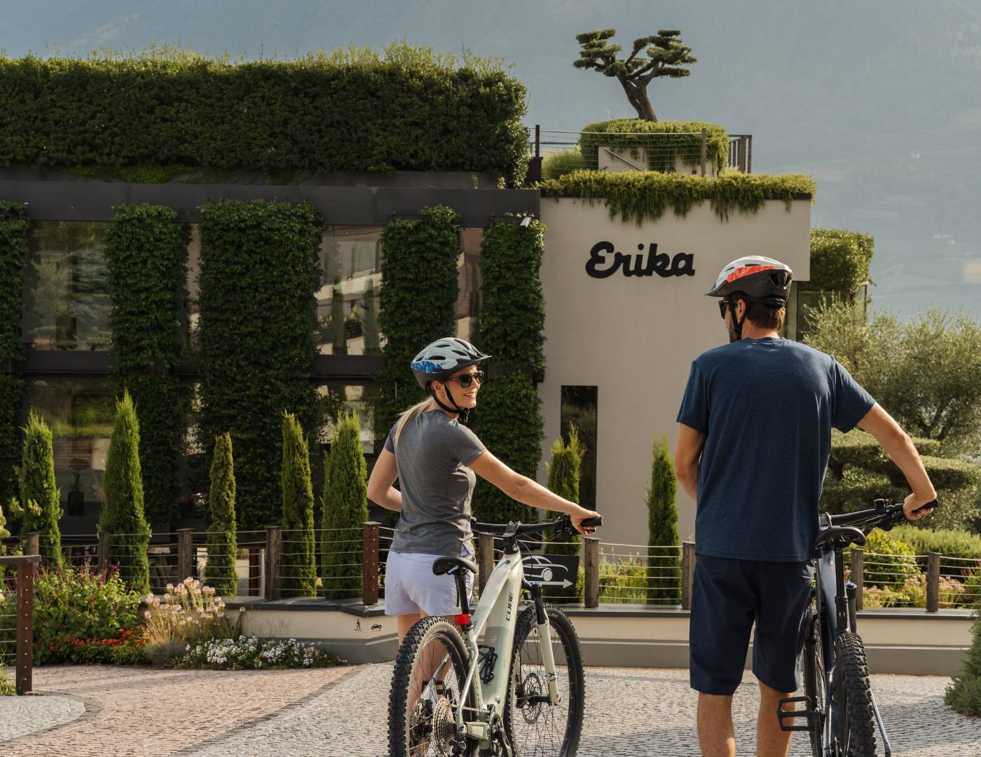 Pärchen mit dem Fahrrad vor der Einfahrt des Spa & Relax Hotel Erika