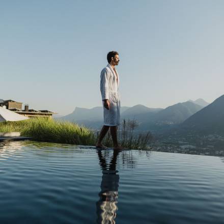 Mann im Bademantel spaziert am Infinity-Pool im 5 Sterne Wellnesshotel in Meran, Südtirol