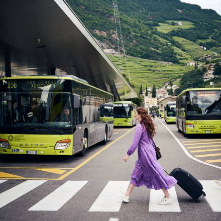 Frau mit Koffer am Busbahnhof – bequeme Anreise mit dem Bus nach Meran