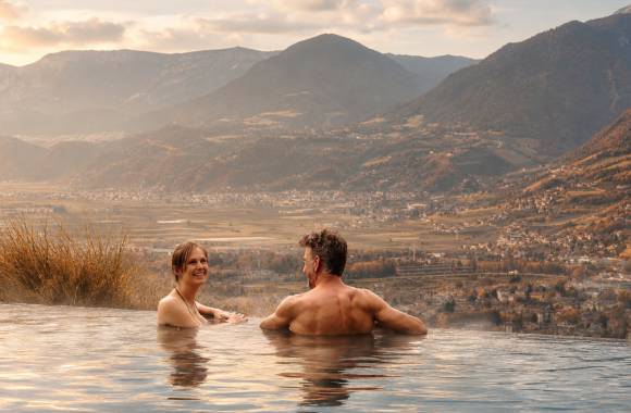 Pärchen entspannt im Infinity-Pool bei bestem Novemberwetter im Wellnesshotel in Südtirol