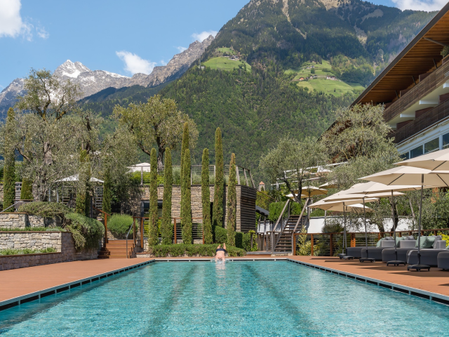 Schwimmer springt dynamisch in das 25-Meter-Sportbecken des Hotel Erika in Dorf Tirol
