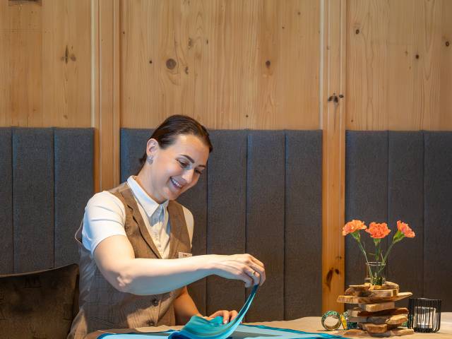 Service-Fachkraft Adrien faltet Servietten für den Abendservice im Restaurant des Hotel Erika in Dorf Tirol