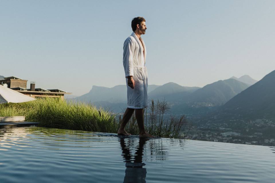 Mann im Bademantel spaziert am Infinity-Pool im 5 Sterne Wellnesshotel in Meran, Südtirol