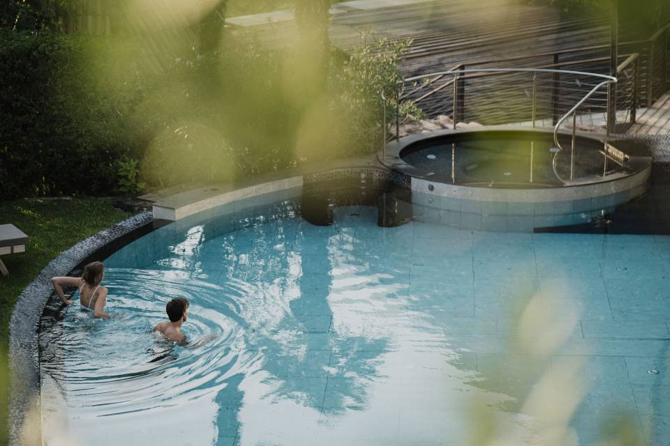 Coppia che si rilassa nella piscina all’aperto dell’Hotel Erika a Tirolo