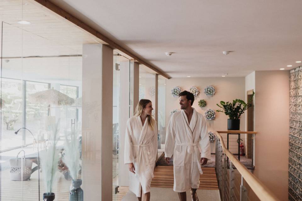 Pärchen geht Hand in Hand im Bademantel durch das Hotel Erika und genießt den Wellnessurlaub
