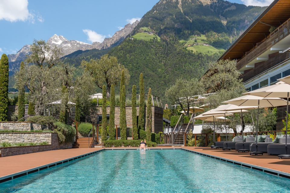 Schwimmer springt dynamisch in das 25-Meter-Sportbecken des Hotel Erika in Dorf Tirol