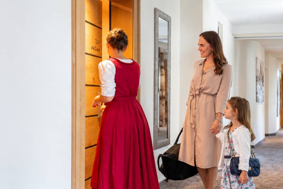 Rezeptionistin begleitet eine Familie zu ihrem Zimmer im Familienhotel in Südtirol